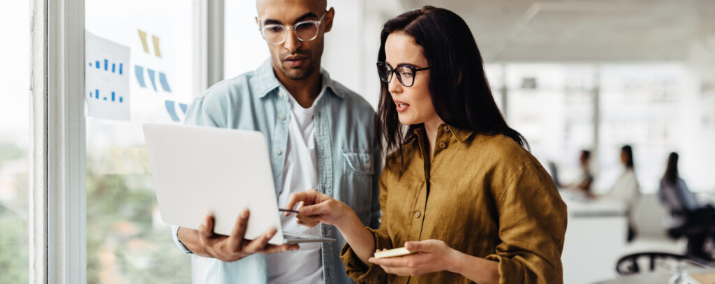 Business people standing in an office and using a laptop AdobeStock 662698178