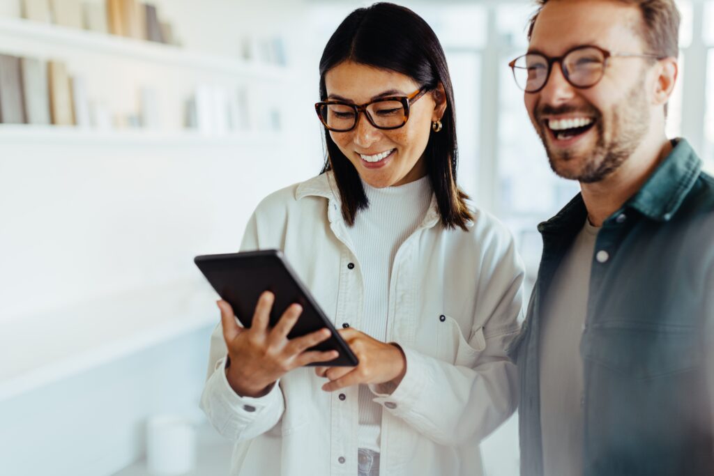 Female designer standing with her colleague and using a tablet AdobeStock 687900379 1
